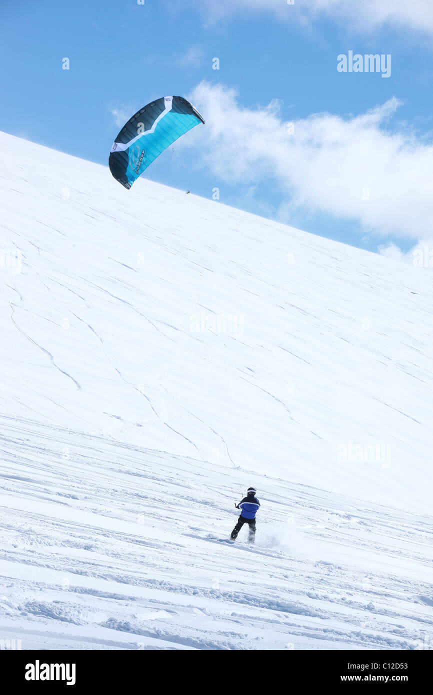 Snowkite équitation dans les montagnes de l'Utah. Voile bleu vif et bleu ciel au-dessus des montagnes couvertes de neige. Banque D'Images