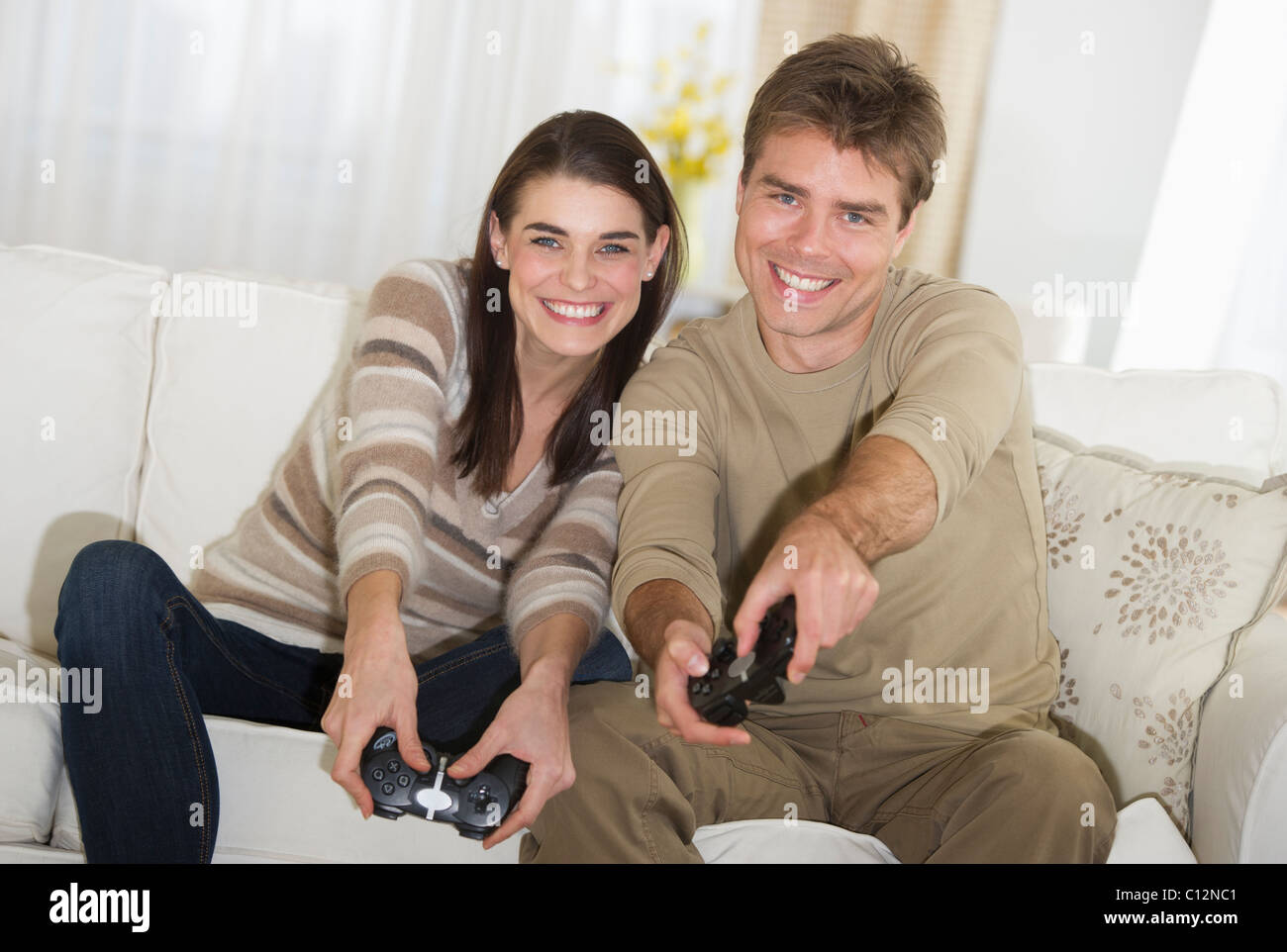 USA, New Jersey, Jersey City, Couple sitting on sofa, jouer à des jeux vidéo Banque D'Images