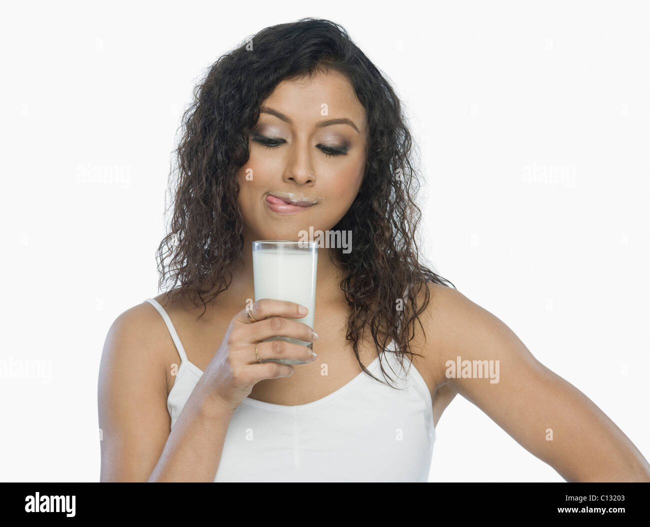 Femme tenant un verre de lait et lécher les lèvres Banque D'Images