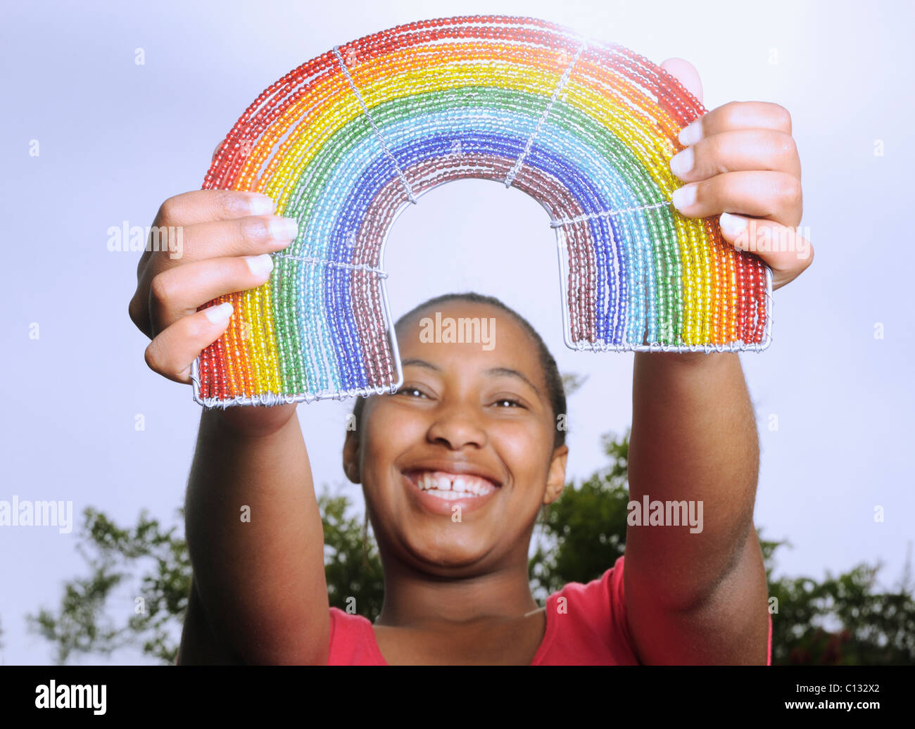 Teenage girl holding up une robe arc-en-ciel. Cape Town, Afrique du Sud Banque D'Images