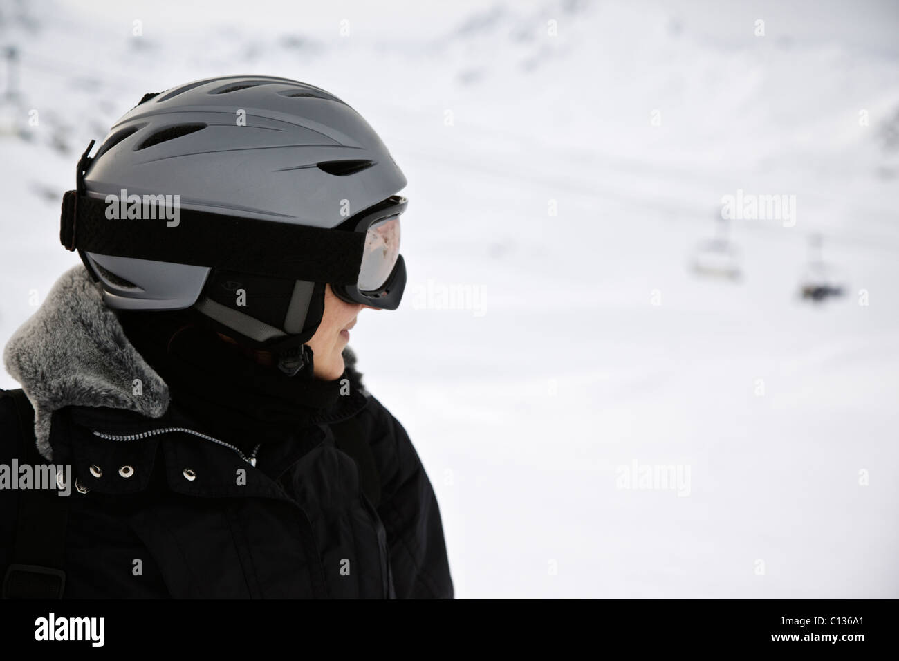 Profil de skieur femelle en sécurité, casque, lunettes et combinaison de ski noire dans la station française de Val d'Isère Banque D'Images