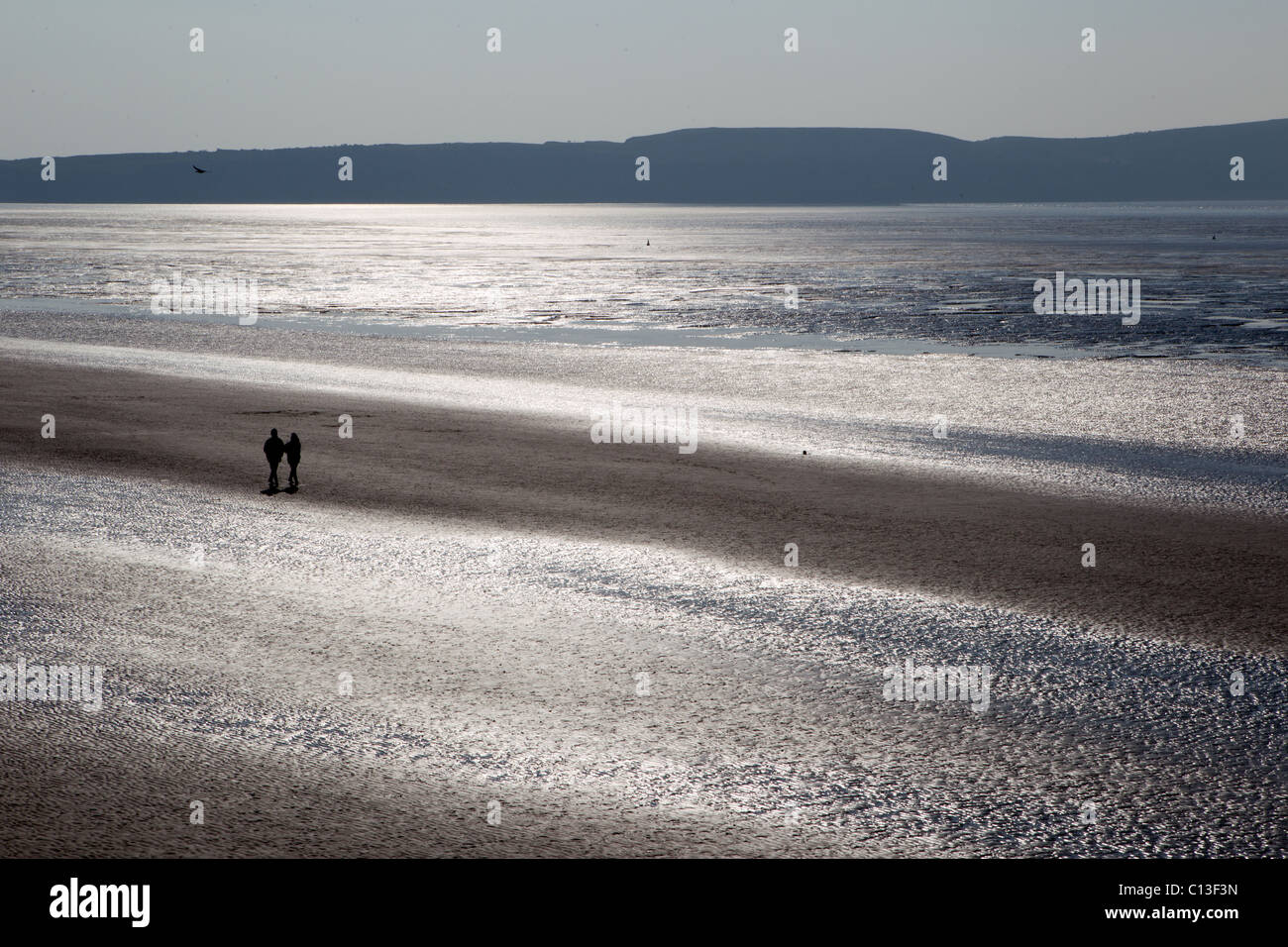 Un couple romantique marche sur Weston Super Mare Beach que le soleil brille dans l'heure d'été Banque D'Images