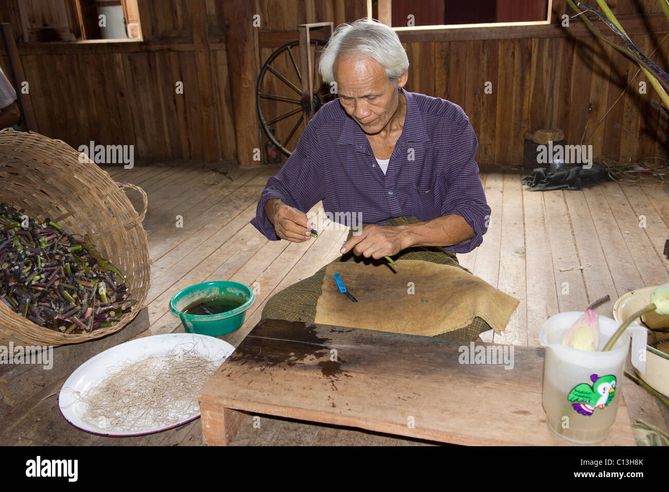 L'homme de l'extraction à partir de filaments textiles fleur de lotus, Paw Khone village, lac Inle, Birmanie Myanmar Banque D'Images