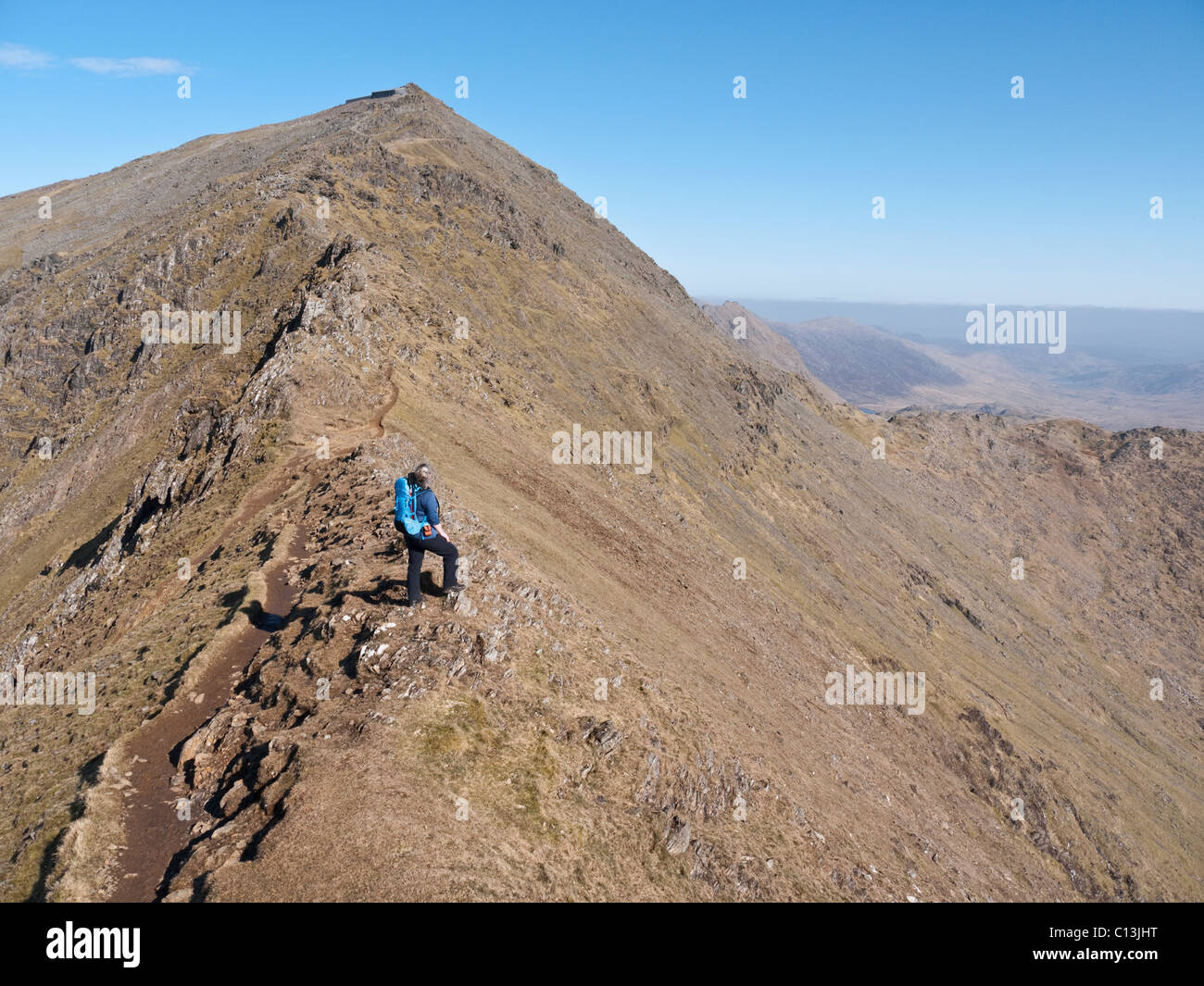 Une femelle hill walker admire la vue de Bwlch Main sur la crête sud Snowdon. Le café, Hafod Eryri peut être vu sur le sommet. Banque D'Images