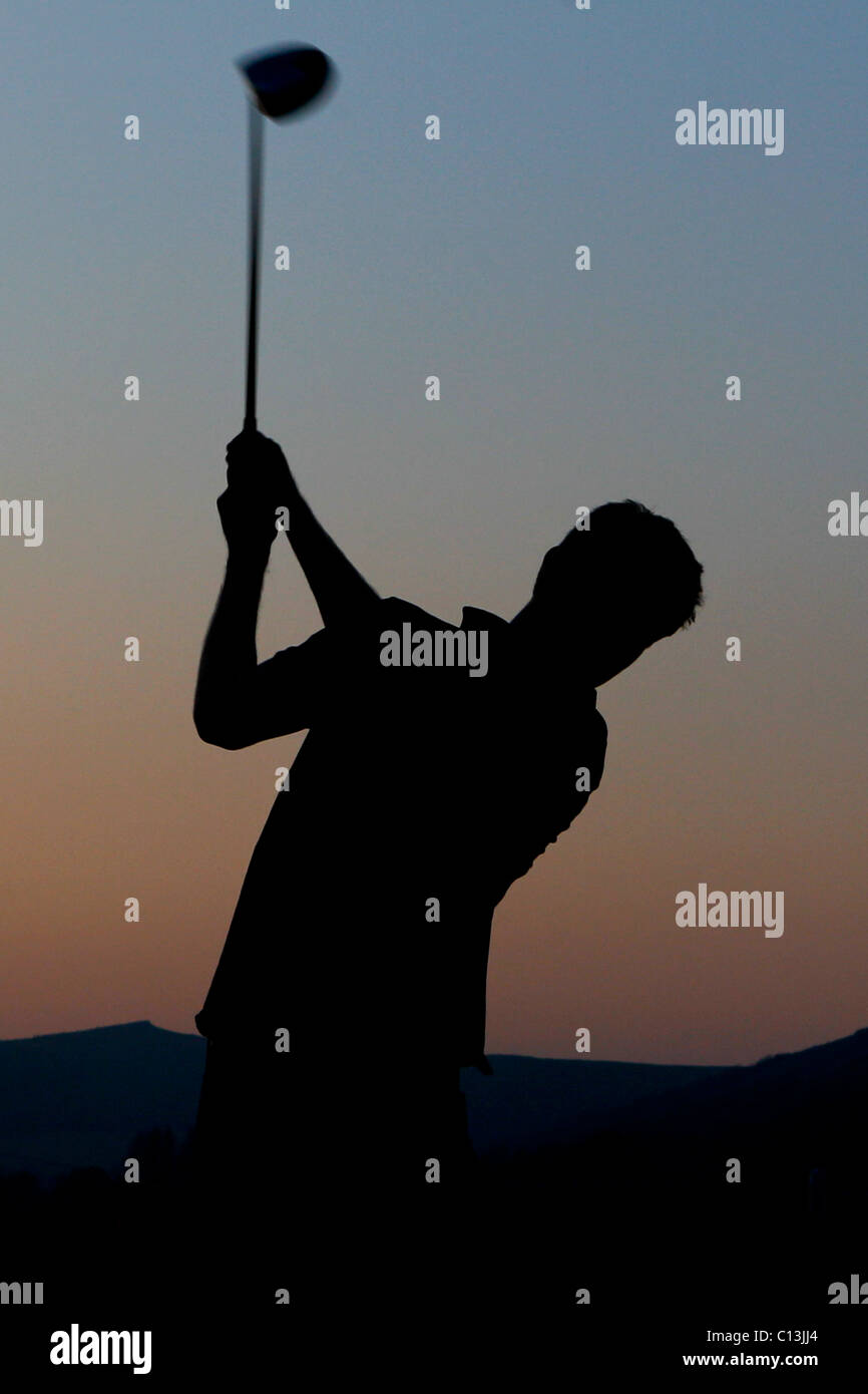 L'homme jouer au golf avec un magnifique paysage autour de lui comme le soleil se couche Banque D'Images