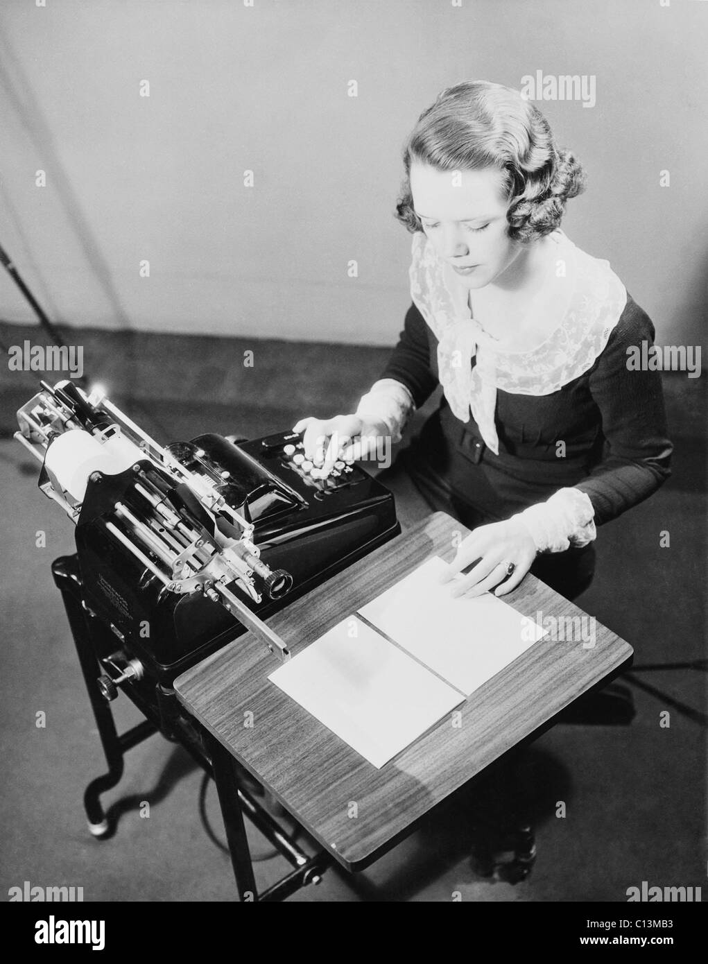 Jeune femme fonctionnaire à l'aide d'une calculatrice. Ca. 1935. Banque D'Images