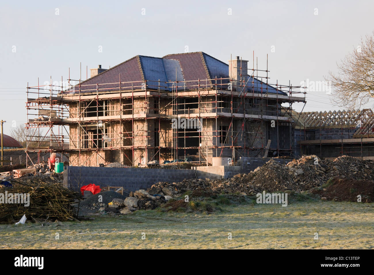 Un échafaudage sur une grande maison neuve en cours de construction sur un terrain vert site. Pays de Galles, Royaume-Uni, en Grande-Bretagne, en Europe. Banque D'Images
