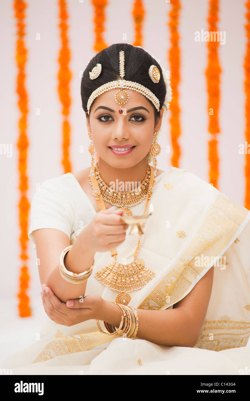 Portrait d'une jeune mariée en priant avec une lampe à huile et souriant Banque D'Images