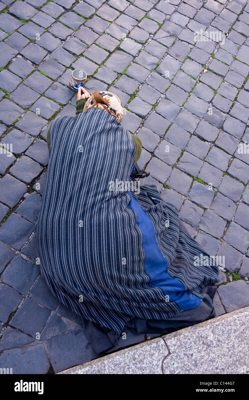 Gypsy femme mendiant gisant sur le pavé de Ponte Sant'Angelo, Rome. Banque D'Images