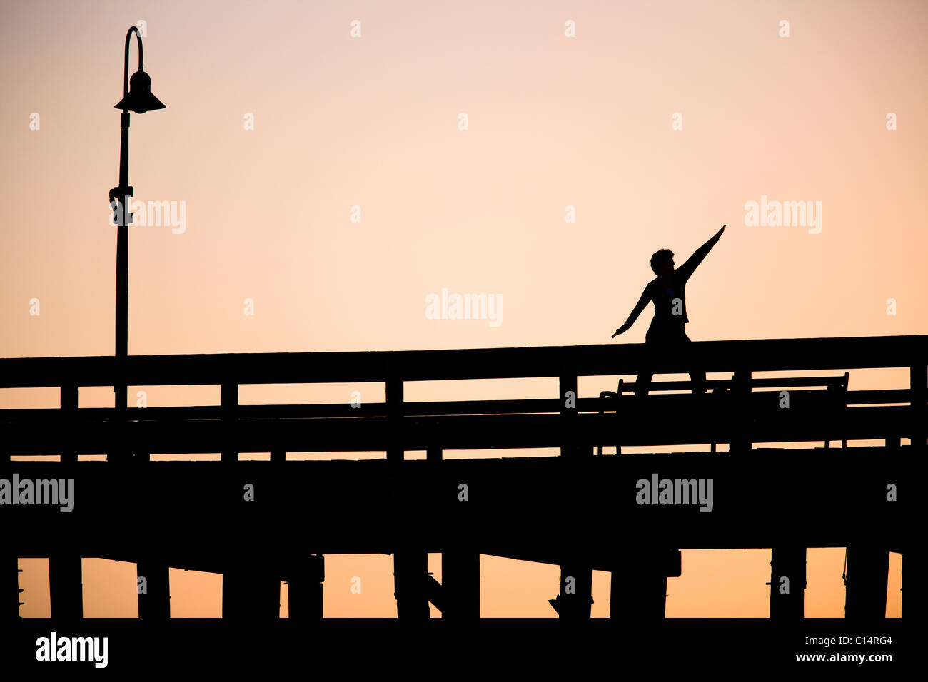 La silhouette d'une femme fait une pose de yoga sur la jetée de Ventura à Ventura, Californie. Banque D'Images