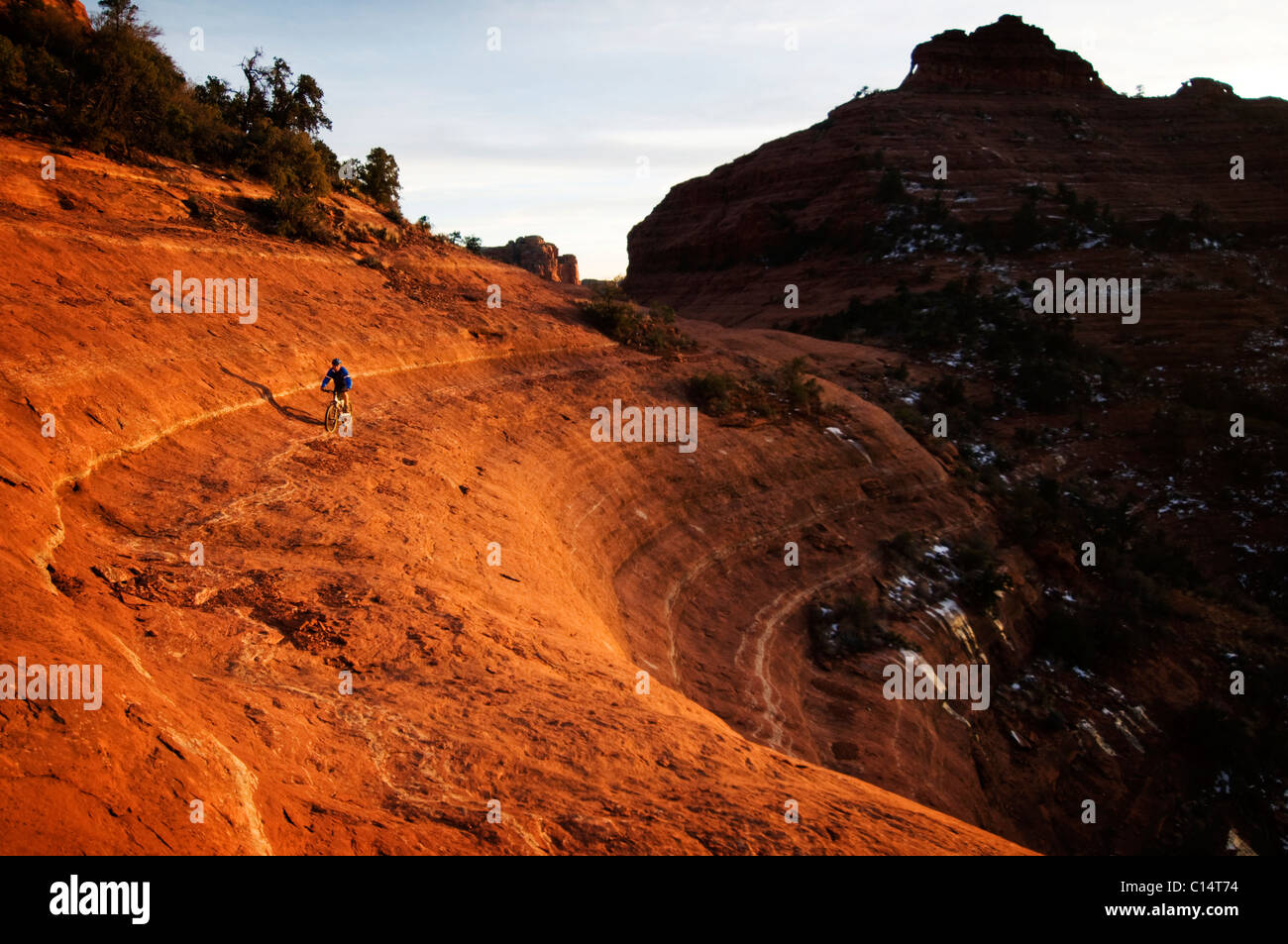 Un homme d'âge moyen chevauche son vtt à travers le red rock country autour de Sedona, Az au coucher du soleil. Banque D'Images