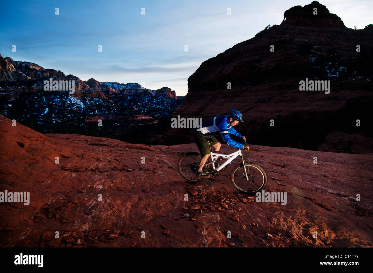 Un homme d'âge moyen chevauche son vtt à travers le red rock country autour de Sedona, Az au coucher du soleil. Banque D'Images