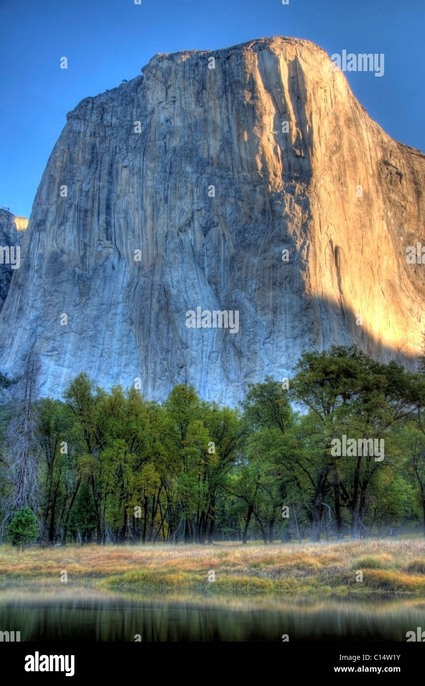 À la recherche sur la rivière Merced, tôt le matin, les rayons du soleil frappent El Capitan dans Yosemite National Park, CA. Banque D'Images