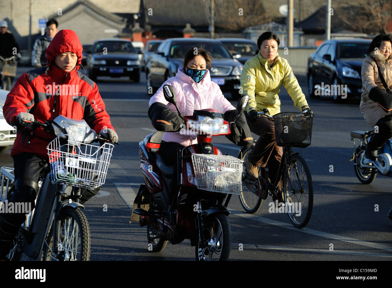 Les gens circuler à bicyclette ou des vélos électriques sur les routes remplies de voitures à Beijing, Chine. 09-Mar-2011 Banque D'Images