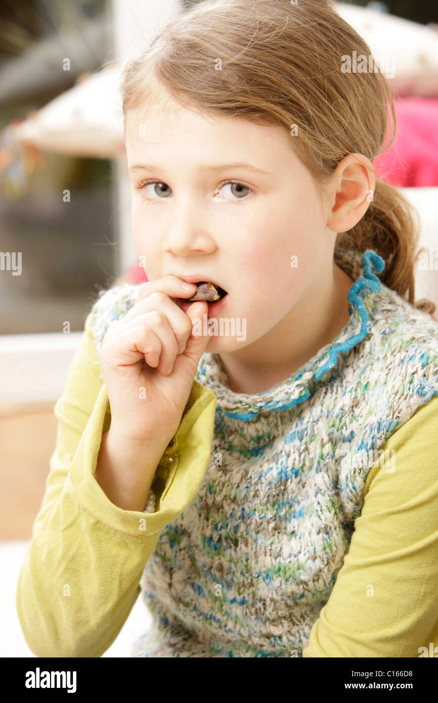 Une fillette de huit ans de manger du chocolat avec une conscience coupable Banque D'Images
