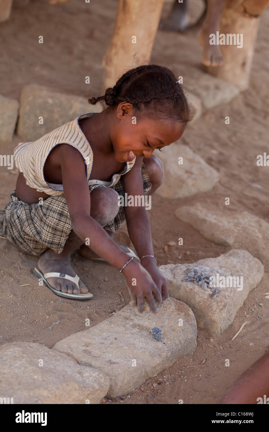 Petite fille casser ou knapping et à l'écaillement des pierres. Mimmicking profession des parents pour la réparation des routes et de la construction. La province de Fianarantsoa. Madagascar. Banque D'Images