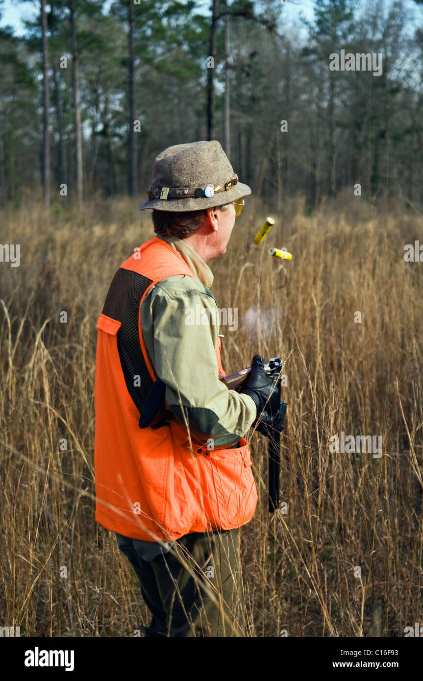 Chasseur d'oiseaux des hautes terres de l'éjection a passé son fusil de coquilles de Colin lors d'une chasse dans le Piney Woods de la Géorgie Banque D'Images