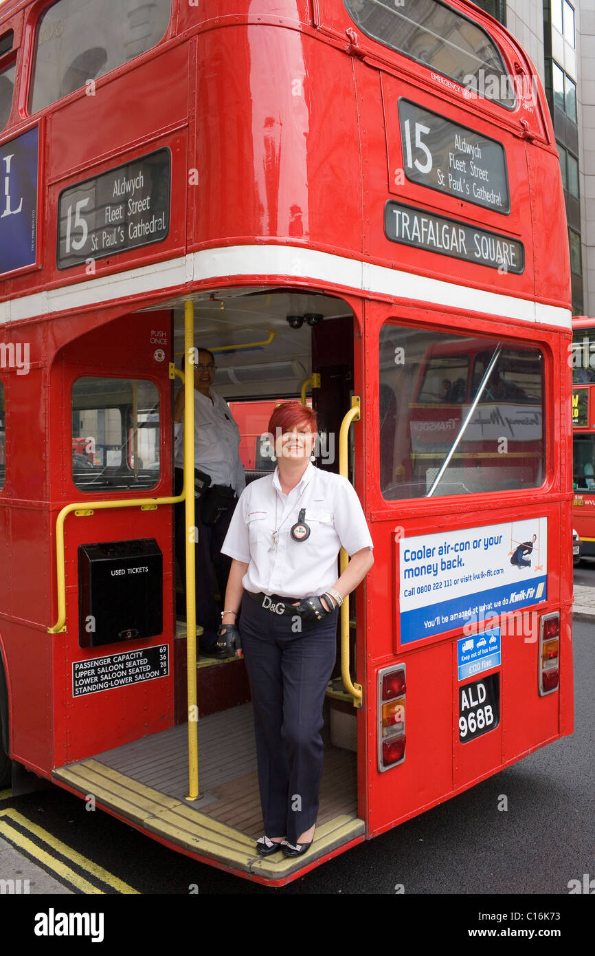 Une femme chef d'orchestre sur l'arrière d'un autobus routemaster rouge à Londres. Banque D'Images