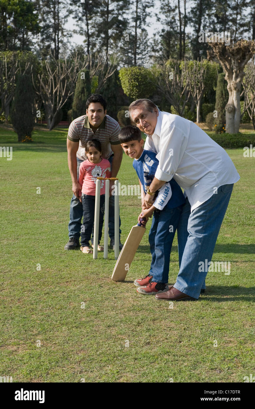 Famille à jouer au cricket in lawn Banque D'Images