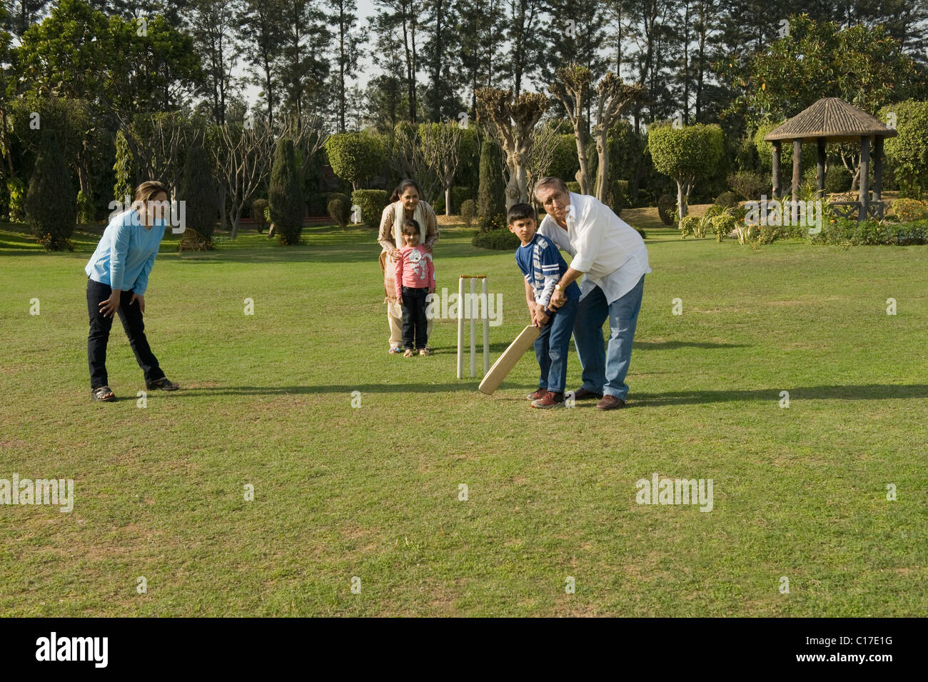 Famille à jouer au cricket in lawn Banque D'Images