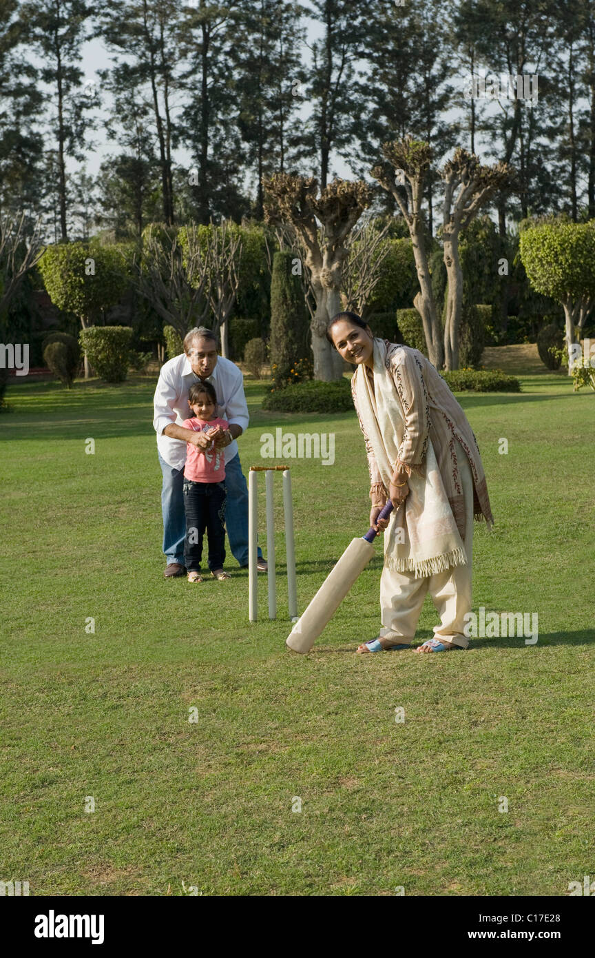 Famille à jouer au cricket in lawn Banque D'Images