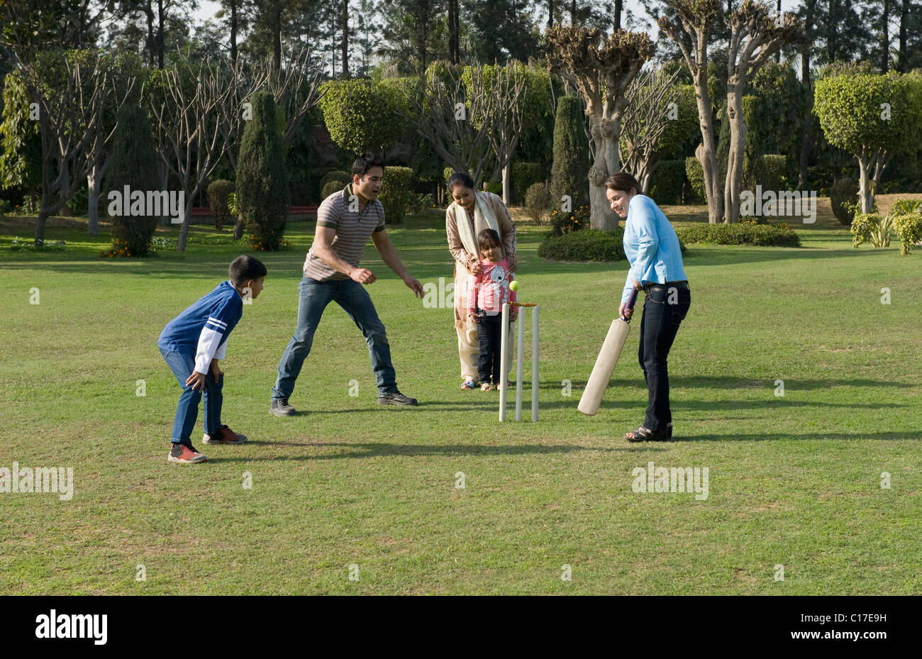 Famille à jouer au cricket in lawn Banque D'Images