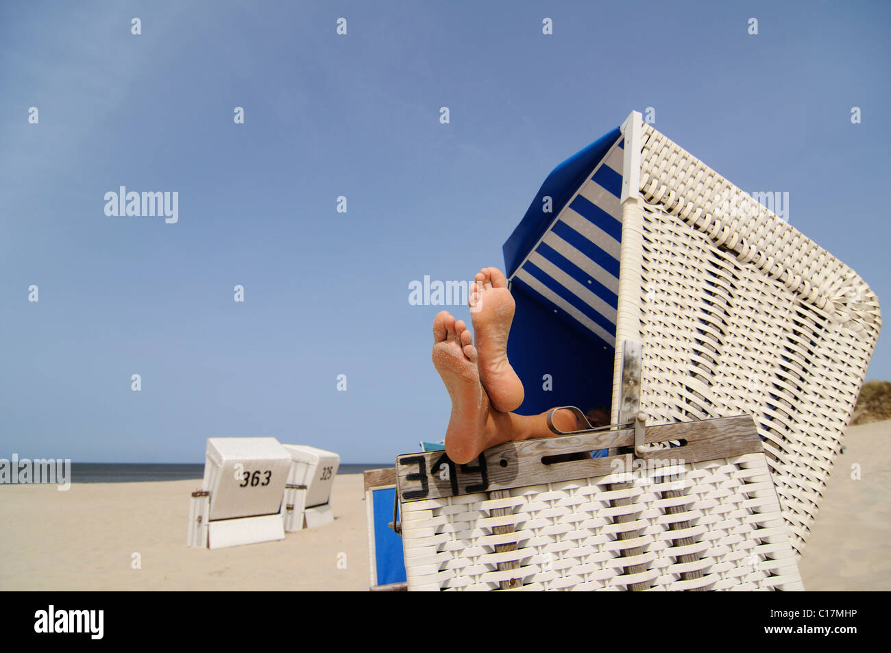 Pieds posés sur une chaise de plage en osier couvert près de Wenningstedt, Sylt, au nord de l'île frisonne, Mer du Nord, Schleswig-Holstein Banque D'Images