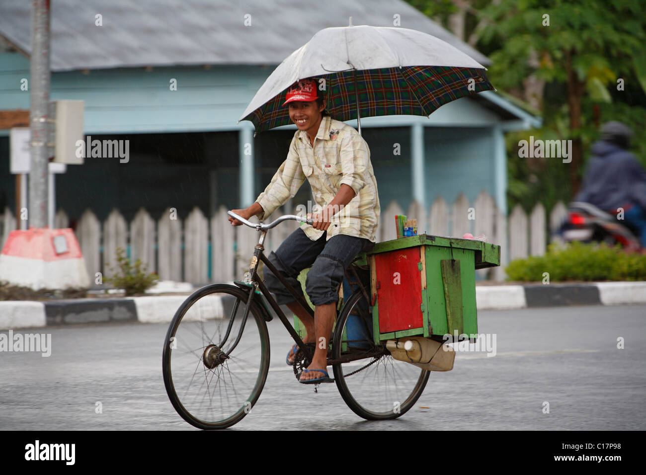 L'homme sur un vélo sous la pluie, parapluie, Pangkalan-Bun, centre de  Kalimantan, Bornéo, Indonésie, Asie du Sud Photo Stock - Alamy