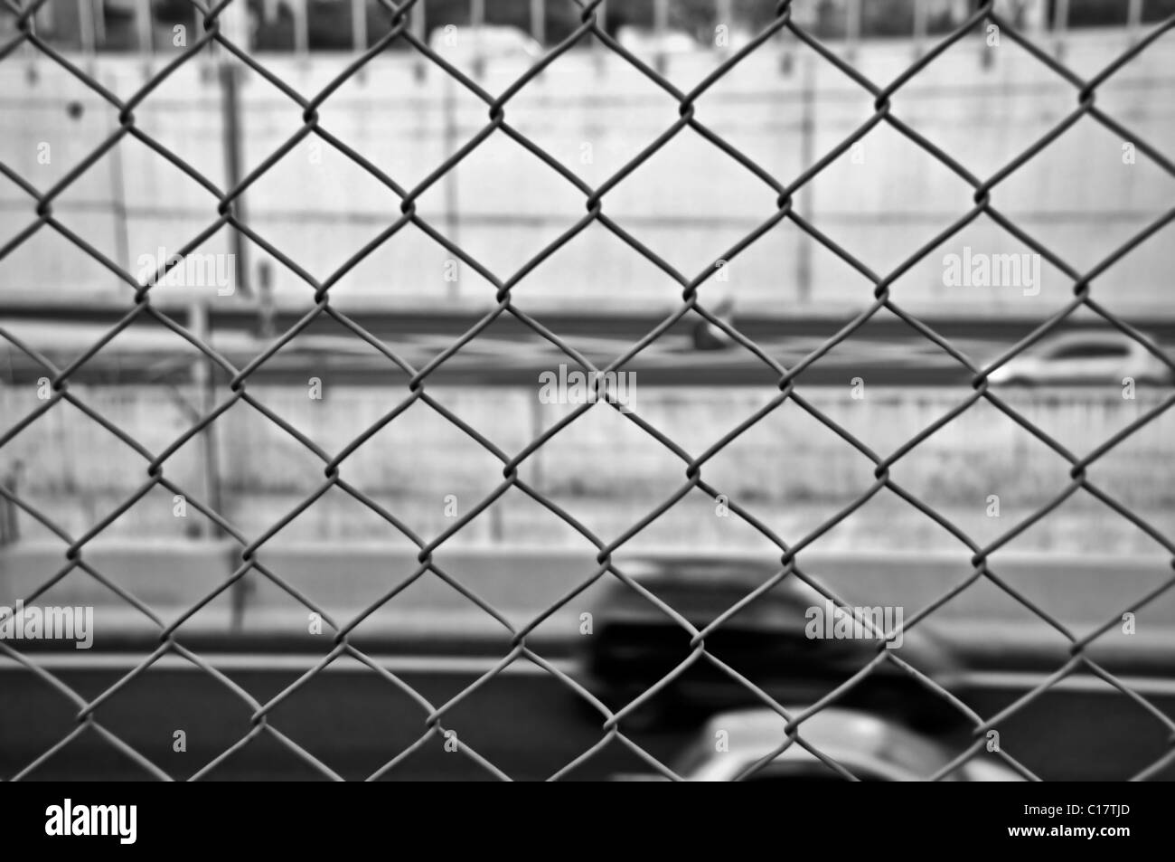 Excès de vitesse des voitures floues sur l'autoroute et Wire Mesh fence. Noir et blanc. Banque D'Images