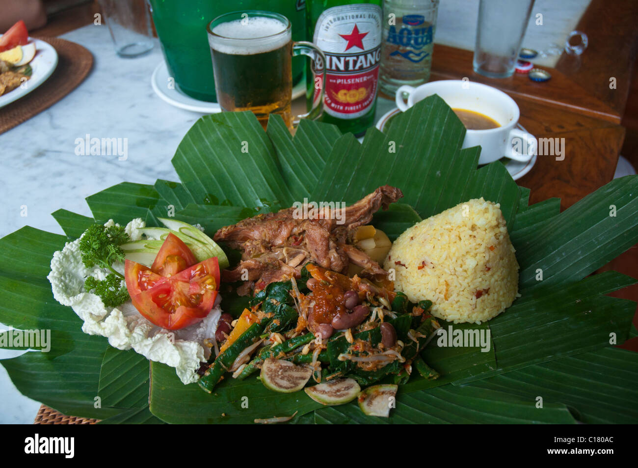 Ragoût de poulet balinais cuit lentement appelé ayam betutu avec riz et salade servi sur des feuilles de bananier vert Banque D'Images