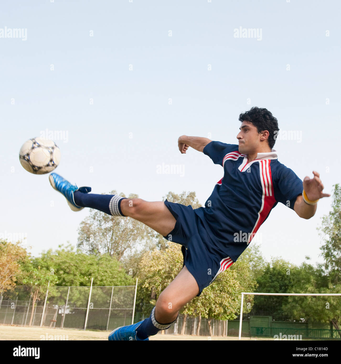 Joueur de football botter un ballon de soccer Banque D'Images