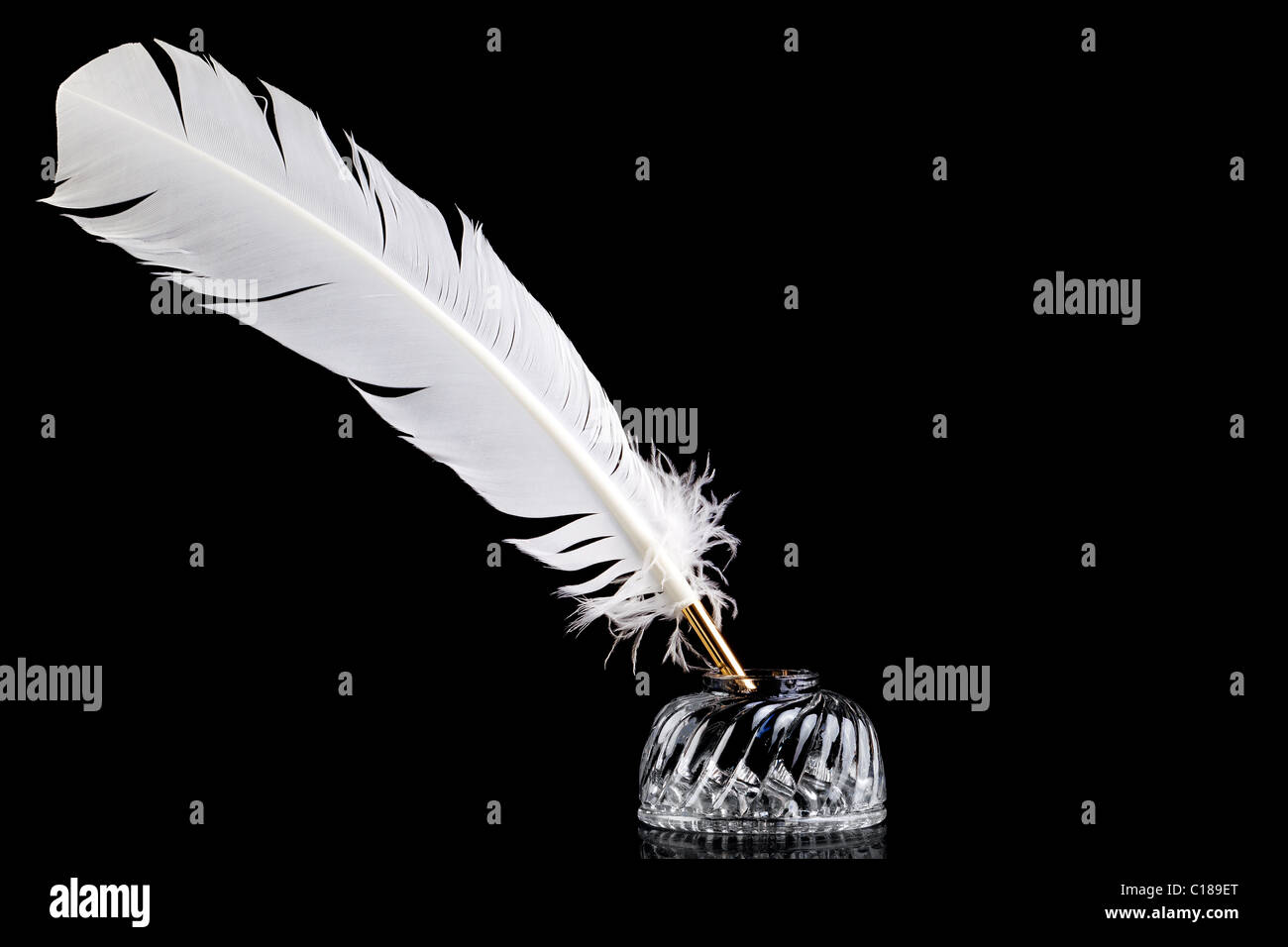 La plume d'une plume blanche et l'encre en cristal bien isolées sur un fond noir. Banque D'Images