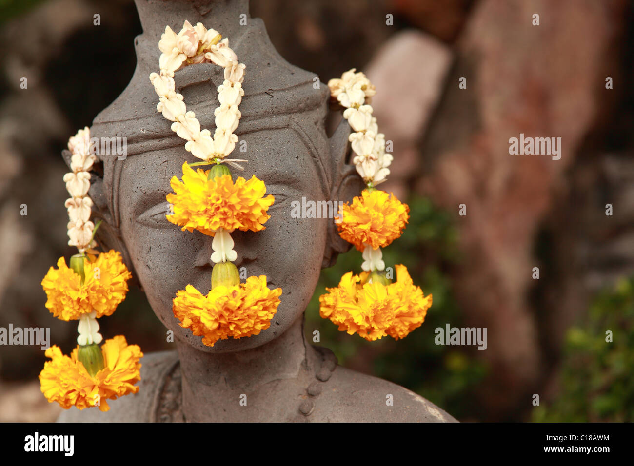 Visage de pierre avec des fleurs Banque D'Images