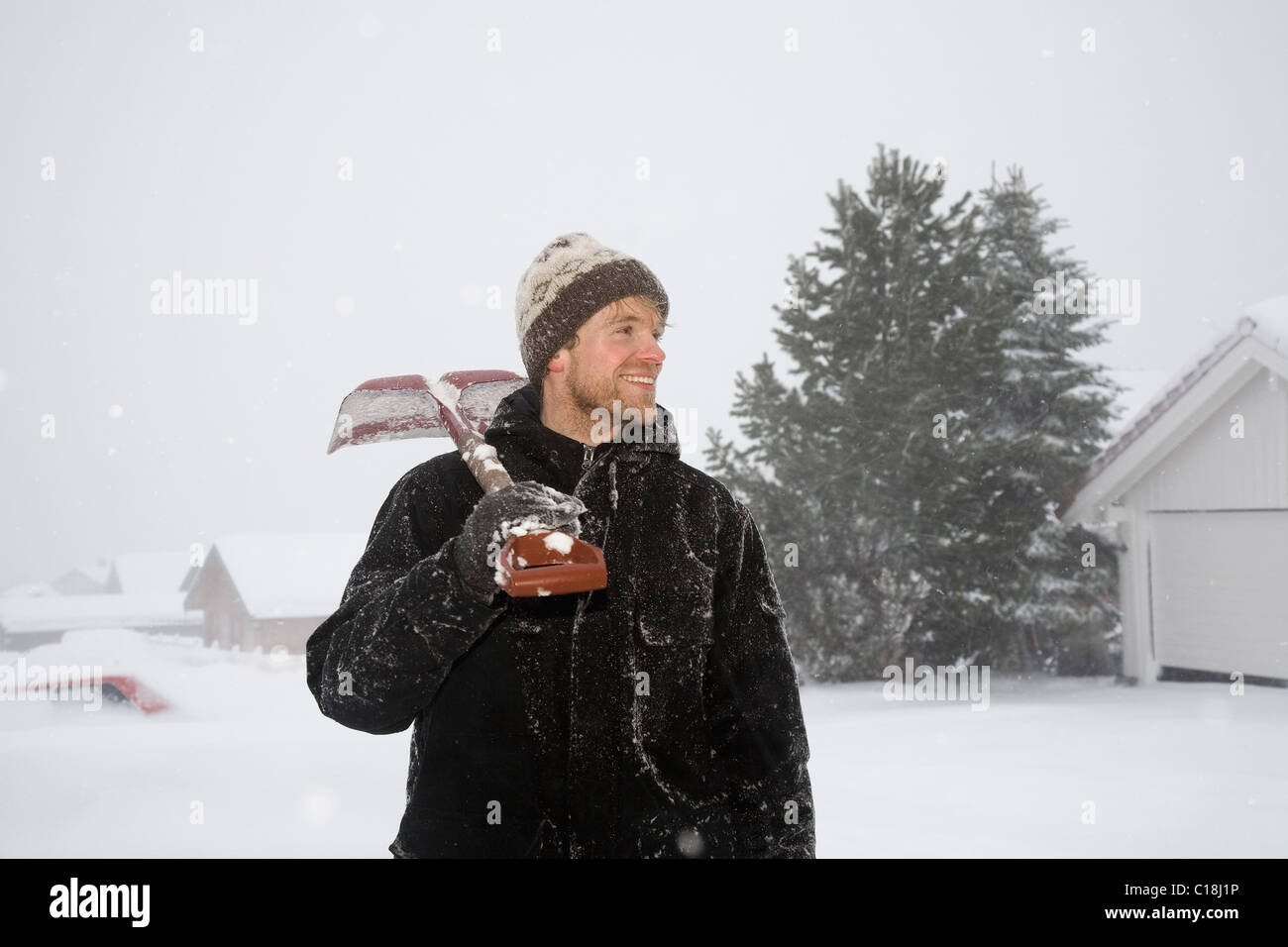 Homme debout avec pelle à neige sur l'épaule Banque D'Images