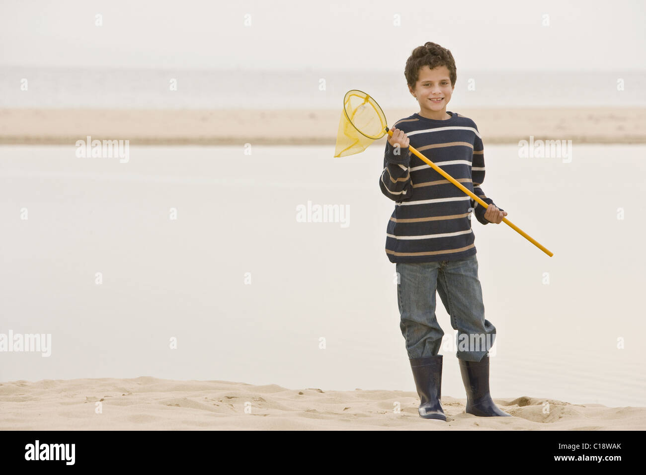 Jeune garçon à beach holding fishing net Banque D'Images