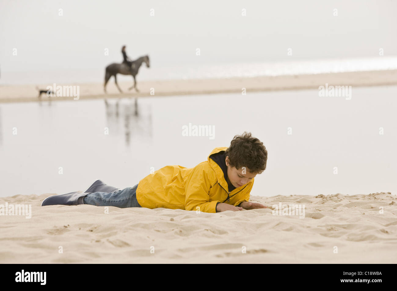 Young boy lying on sand at beach Banque D'Images