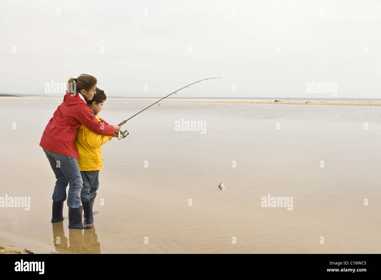 L'enseignement de mère fils à pêcher à la plage Banque D'Images