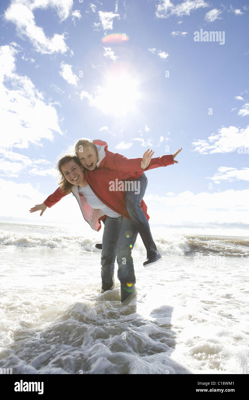 Mère et fille à la plage piggyback ride Banque D'Images
