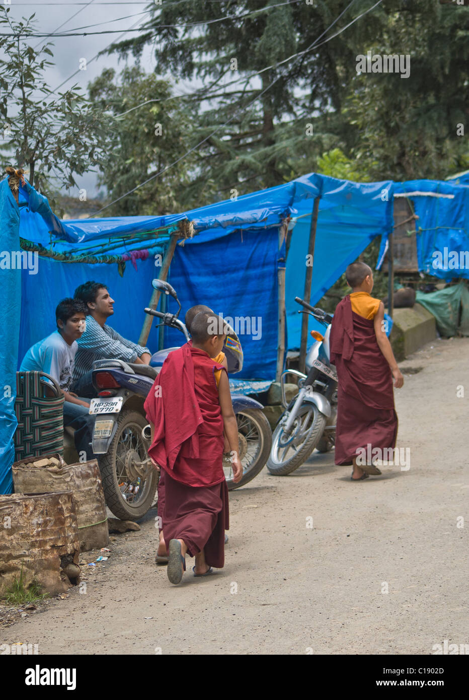 Deux moines bouddhistes tibétains à pied de l'enfant indien passé vendeurs. Banque D'Images