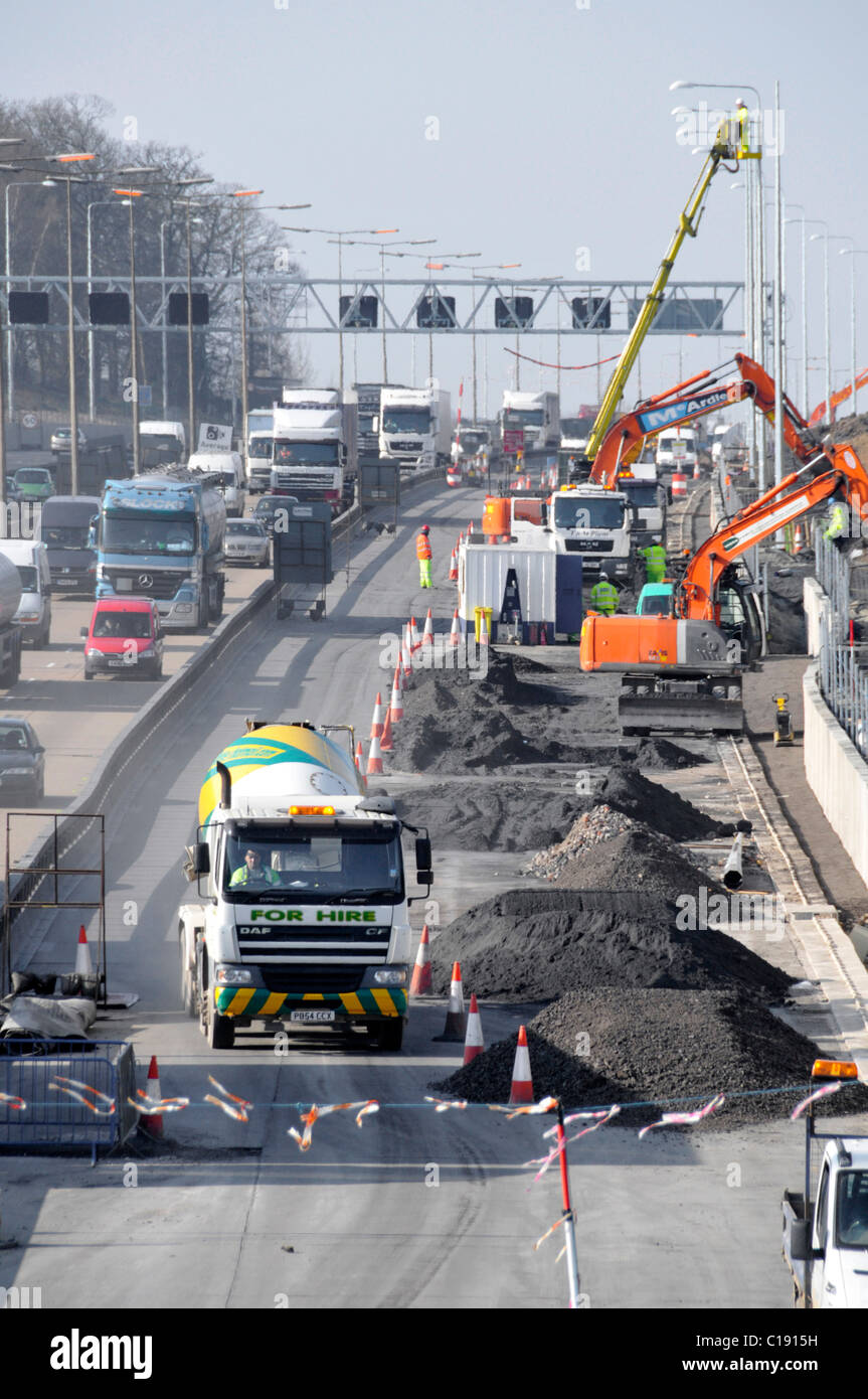 Occupé génie civil élargissement de la route chantier de construction Cherry picker prêt à mélanger béton ciment camions et camions autoroute M25 Essex Angleterre Royaume-Uni Banque D'Images