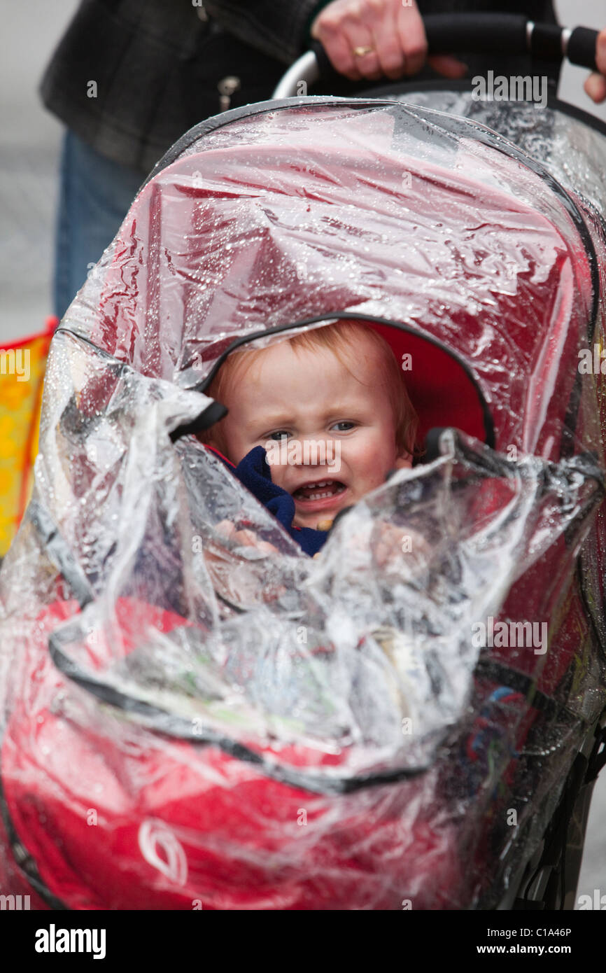 Londres, Angleterre - le jour de la Saint Patrick festival et défilé à Londres, tout-petit dans une poussette, protection contre la pluie Banque D'Images