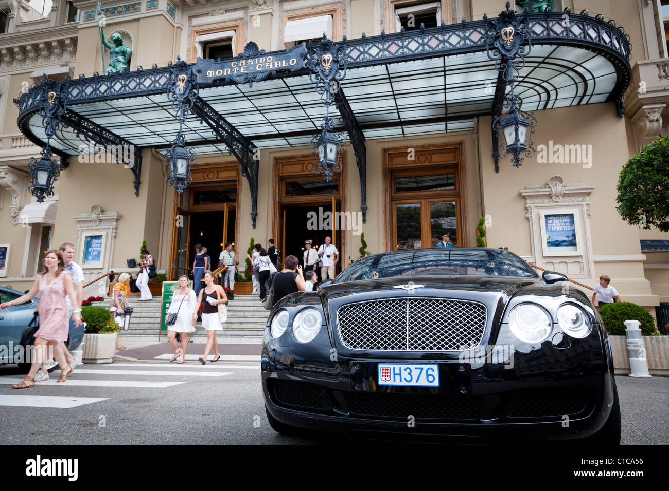 Les touristes viennent et passer par l'entrée au Casino de Monte-Carlo, le remplir avec un coûteux Bentley garée à l'extérieur. Banque D'Images