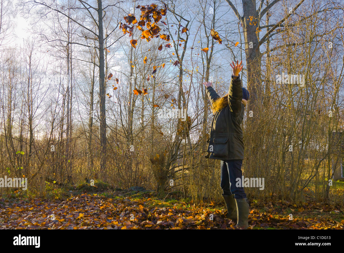 Woman throwing laisse dans l'air à l'automne Banque D'Images