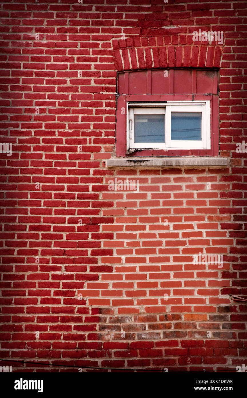 Un vieux mur de brique rouge, repeint et petite fenêtre Banque D'Images