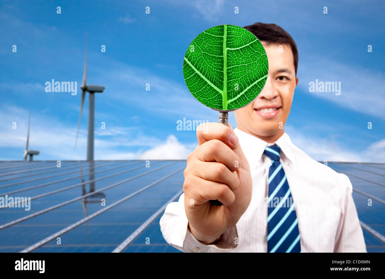 Green Energy business concept.young businessman holding Magnifier et debout devant des panneau solaire et éolienne Banque D'Images