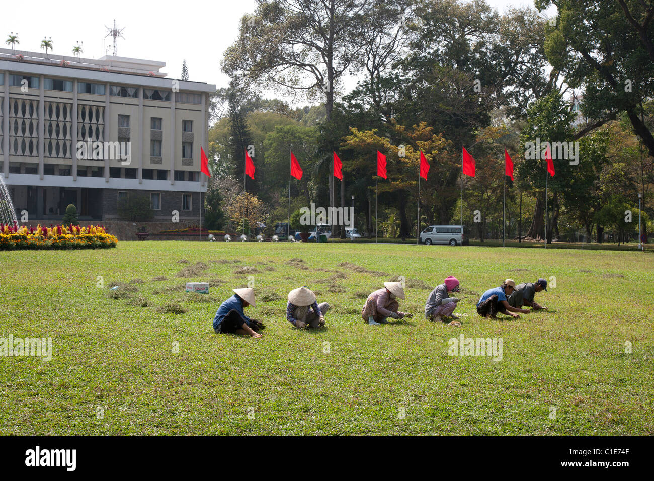 Les gens Arracher les mauvaises herbes à l'avant du Palais de la réunification à Saigon Banque D'Images