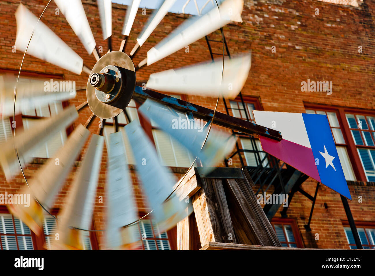 Un moulin à vent avec un drapeau du Texas, que l'on retrouve normalement sur une ferme, monté à l'avant de l'historique hôtel Rogers, San Marcos, Texas. Banque D'Images