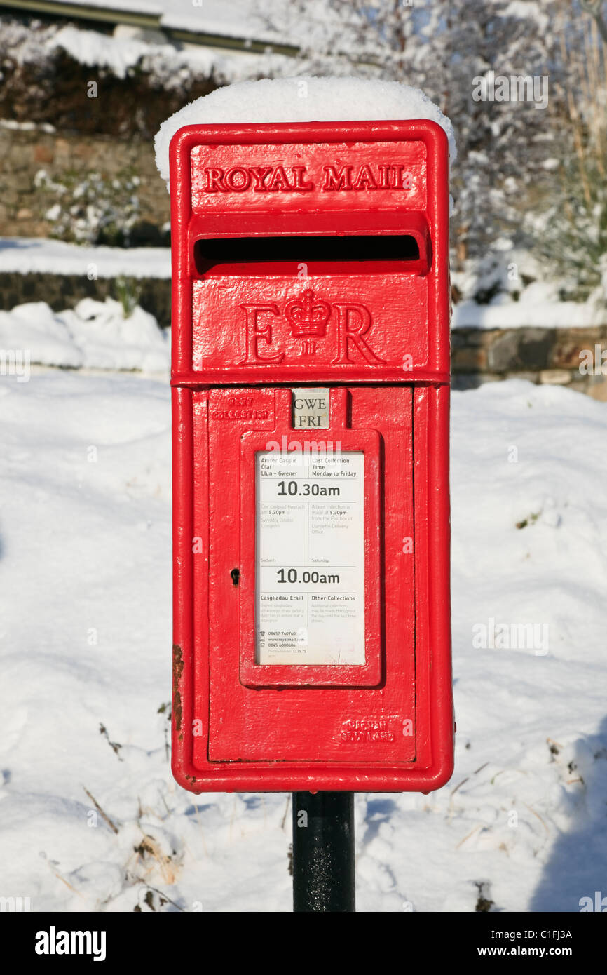 Le Nord du Pays de Galles, Royaume-Uni, Angleterre. Vue frontale d'une boîte aux lettres rouge traditionnelle dans la neige Banque D'Images
