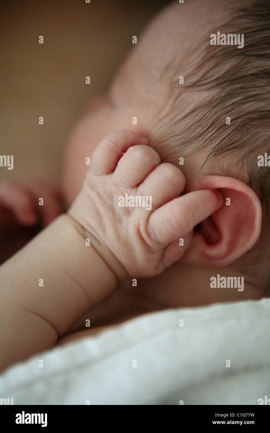 New Born Baby holding ear avec part Banque D'Images
