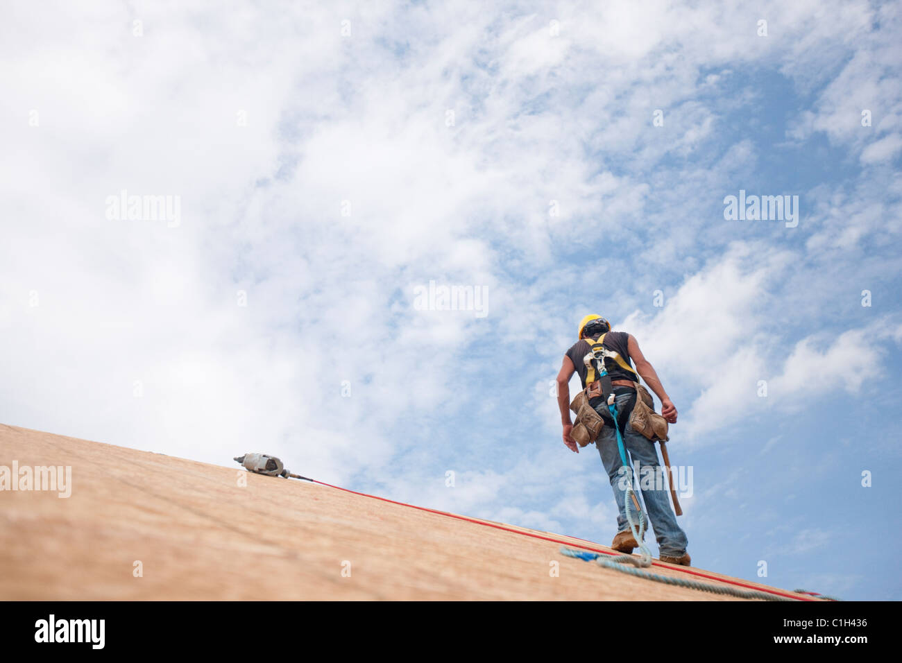 Hispanic carpenter marche sur le toit d'une maison en construction Banque D'Images